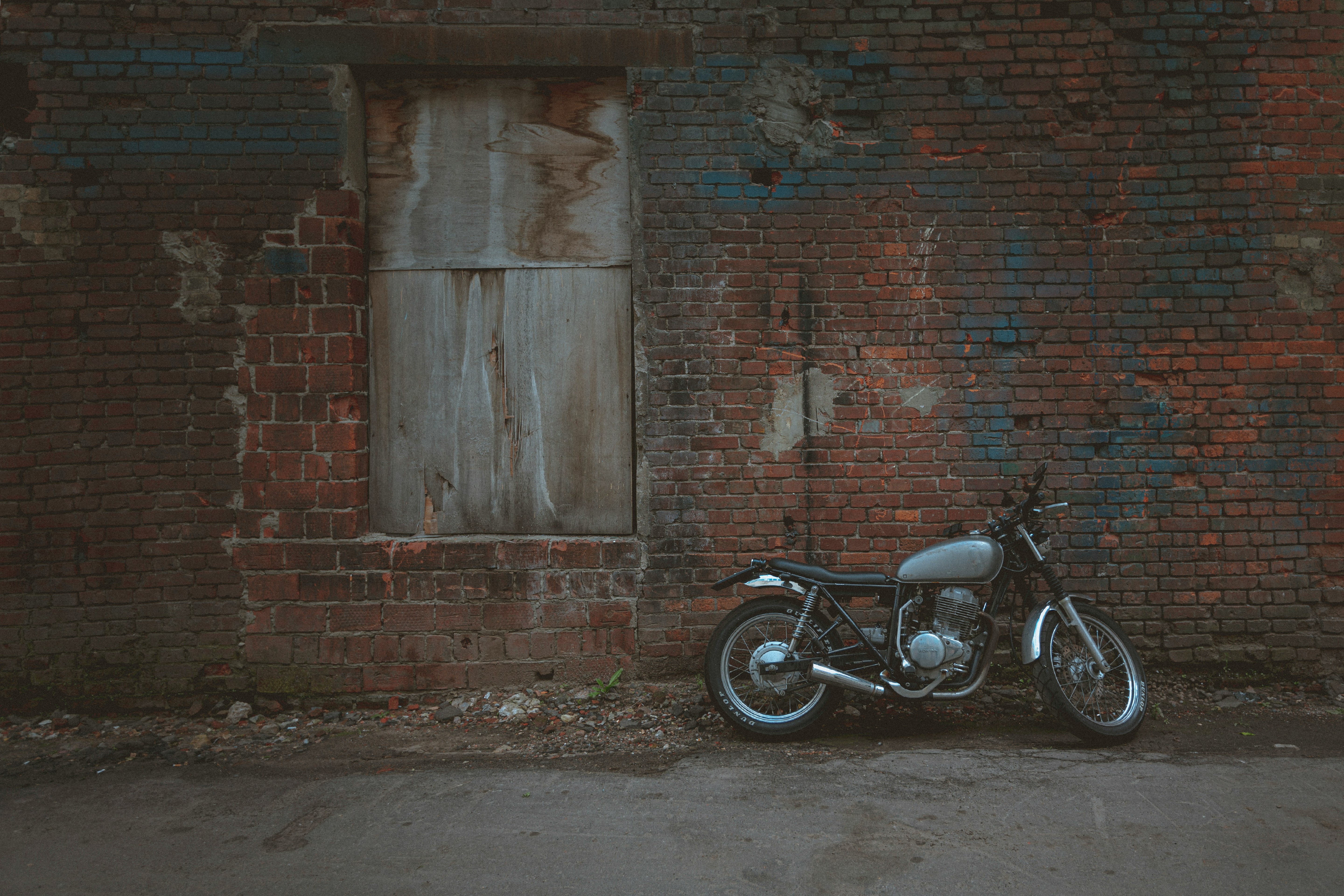 black motorcycle parked beside brown brick wall